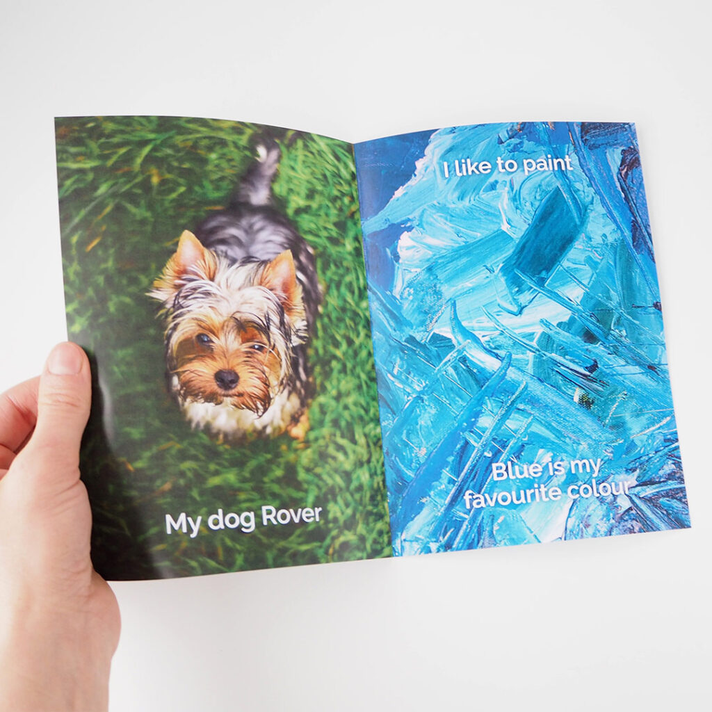 An open book with a small dog on grass on the left side and a blue painting on the right side.